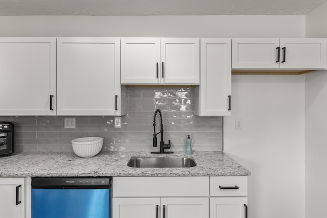 kitchen featuring dishwashing machine, a sink, light stone countertops, and white cabinets