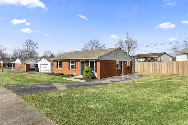 single story home with brick siding, a detached garage, a front yard, fence, and driveway