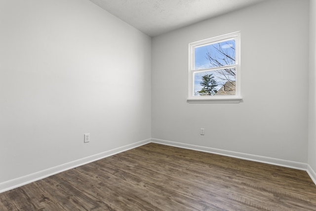 spare room featuring baseboards and dark wood finished floors