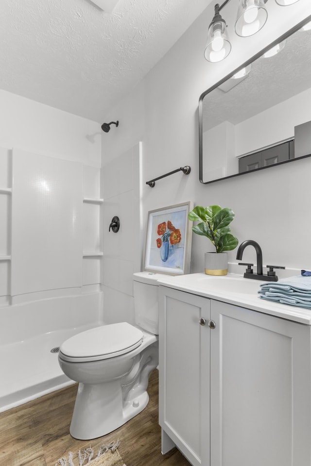 bathroom featuring toilet, a textured ceiling, walk in shower, and wood finished floors