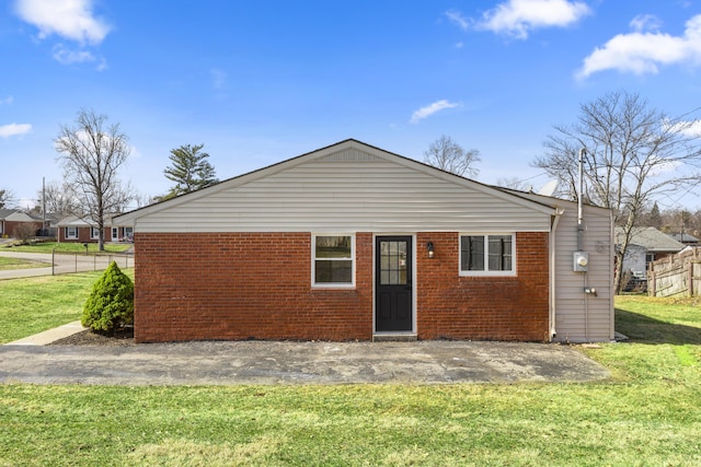 back of house with brick siding and a yard