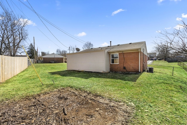 rear view of property featuring a fenced backyard, central AC, a lawn, and brick siding