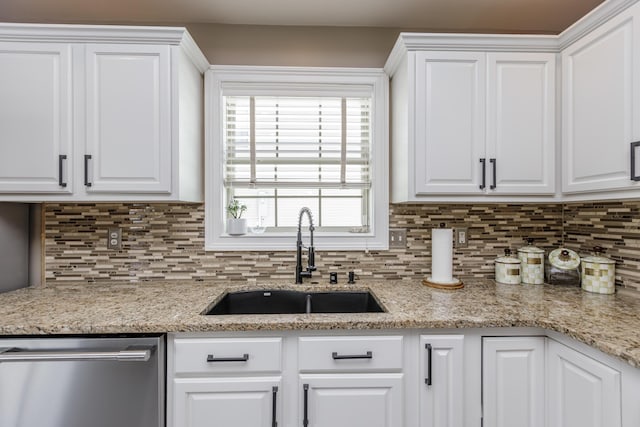 kitchen featuring backsplash, stainless steel dishwasher, white cabinetry, a sink, and light stone countertops