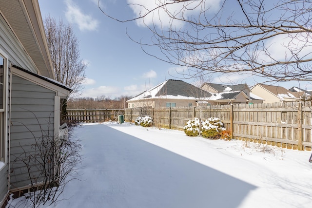 yard layered in snow with a fenced backyard