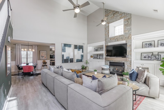 living area featuring built in features, light wood-type flooring, visible vents, and a fireplace