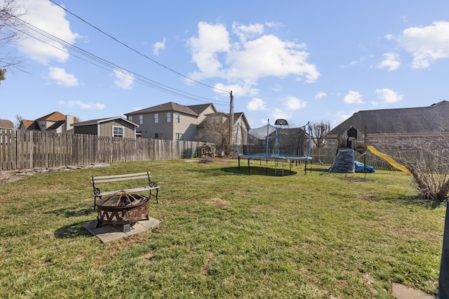 view of yard with a fire pit, a fenced backyard, a residential view, a trampoline, and a playground