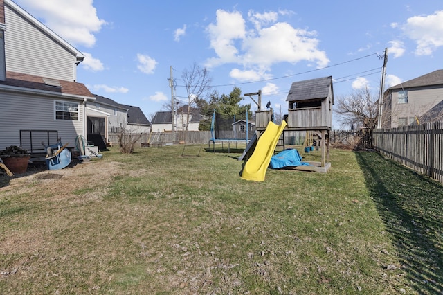 view of yard featuring a trampoline, a playground, and a fenced backyard