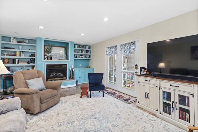 living room featuring built in features, a glass covered fireplace, wood finished floors, and recessed lighting