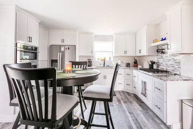 kitchen with light stone counters, tasteful backsplash, stainless steel gas stovetop, and white cabinets