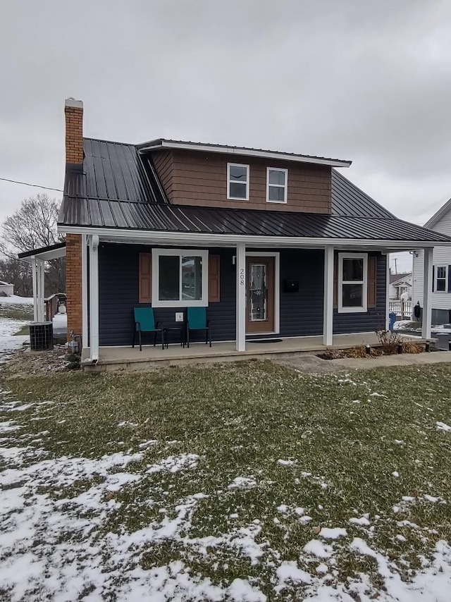 view of front of house with metal roof, a porch, a chimney, and a standing seam roof