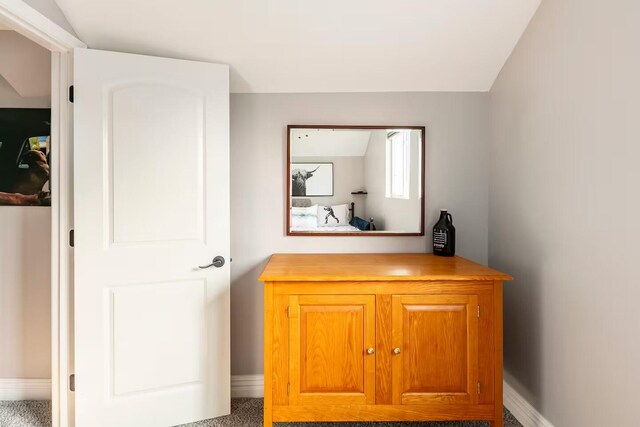 carpeted bedroom featuring baseboards and lofted ceiling