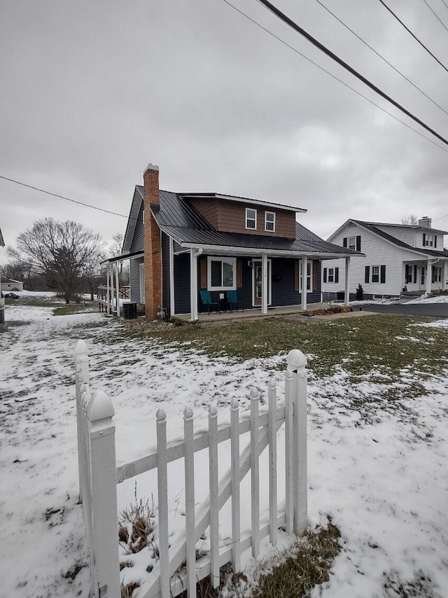 view of front of house featuring a chimney, covered porch, and metal roof