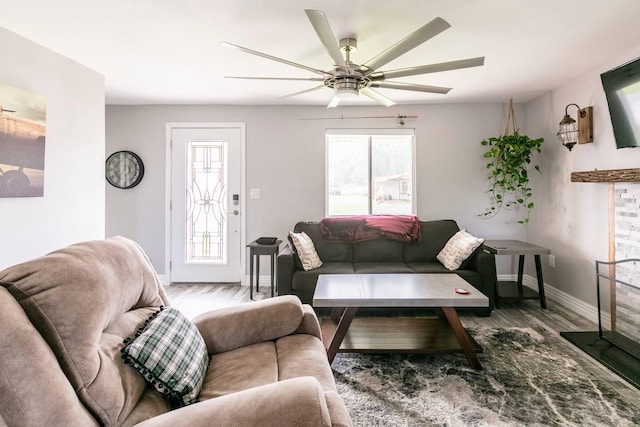 living room with plenty of natural light, wood finished floors, baseboards, and ceiling fan