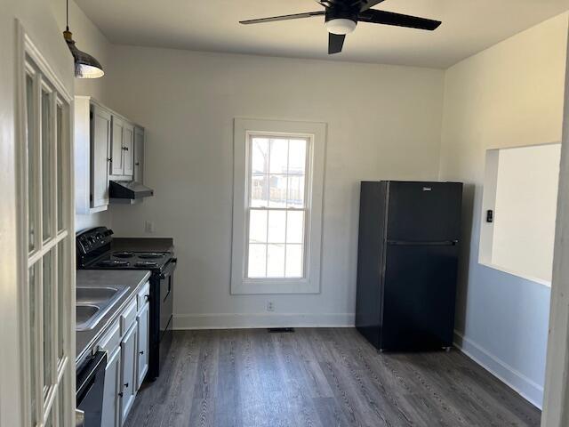 kitchen with a ceiling fan, dark wood-style floors, baseboards, black appliances, and under cabinet range hood