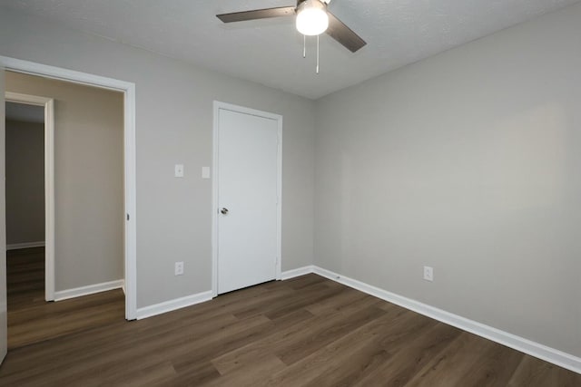 unfurnished bedroom with dark wood-style floors, baseboards, and a ceiling fan