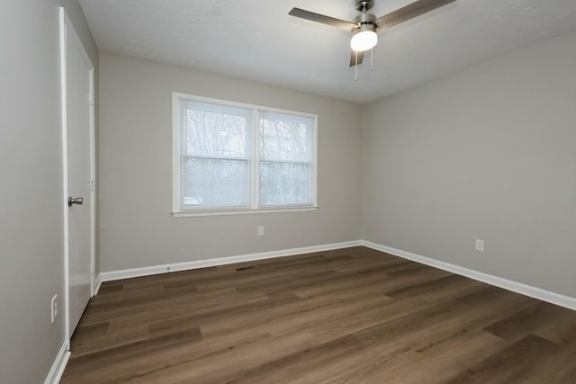 spare room featuring ceiling fan, dark wood finished floors, and baseboards