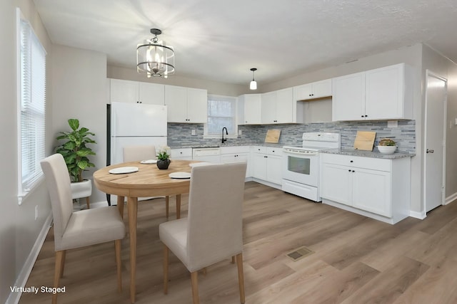 kitchen with light wood-type flooring, white appliances, white cabinetry, and decorative light fixtures