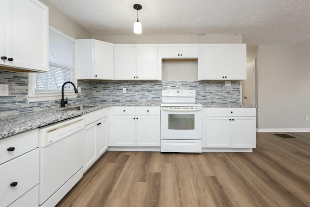 kitchen with decorative light fixtures, light wood finished floors, white cabinetry, a sink, and white appliances