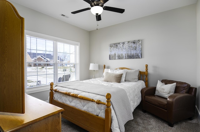 bedroom featuring visible vents, dark carpet, and a ceiling fan