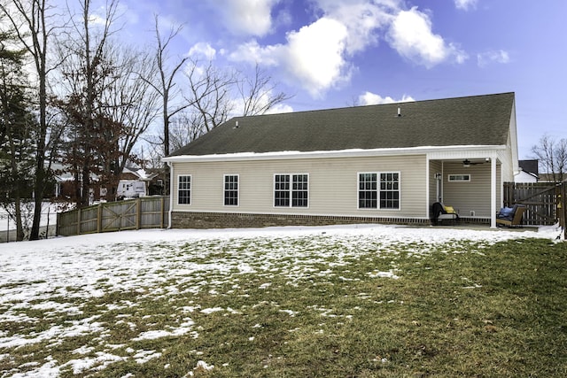 snow covered property featuring brick siding, fence, and a yard