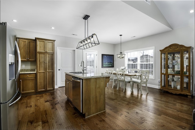 kitchen featuring a kitchen island with sink, stainless steel appliances, dark wood-type flooring, a sink, and decorative light fixtures