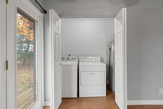 washroom with laundry area, baseboards, light wood-type flooring, water heater, and separate washer and dryer