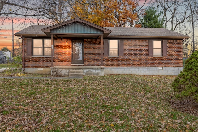 view of front of property with crawl space, a yard, a shingled roof, and brick siding