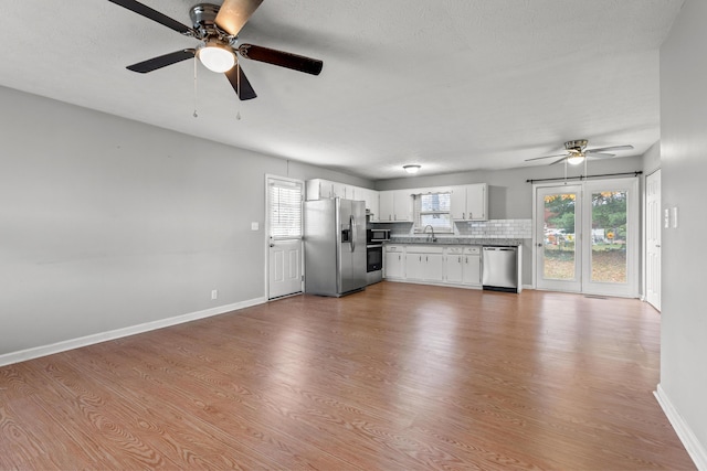 unfurnished living room featuring a sink, ceiling fan, light wood-style flooring, and baseboards