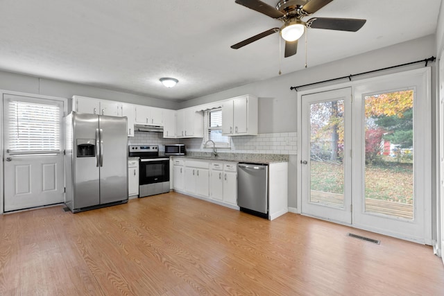 kitchen with stainless steel appliances, visible vents, white cabinetry, light wood-type flooring, and under cabinet range hood