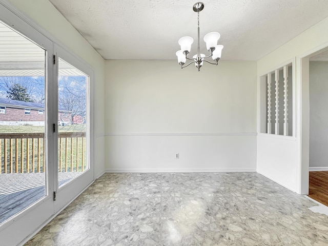 empty room with a textured ceiling, plenty of natural light, baseboards, and a notable chandelier