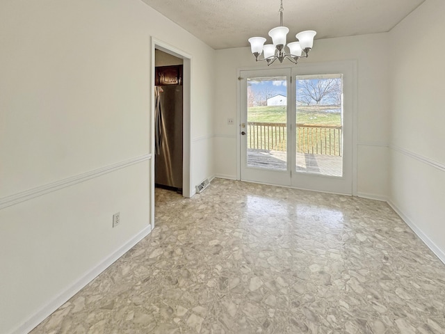 unfurnished dining area featuring a chandelier, a textured ceiling, and baseboards