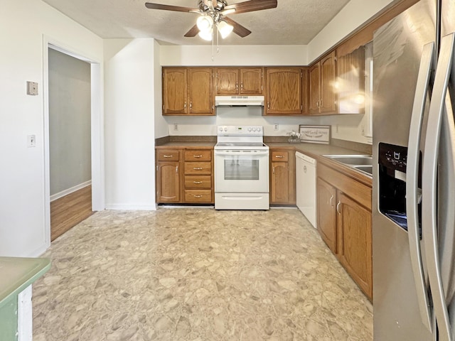 kitchen featuring white appliances, under cabinet range hood, brown cabinetry, and a textured ceiling