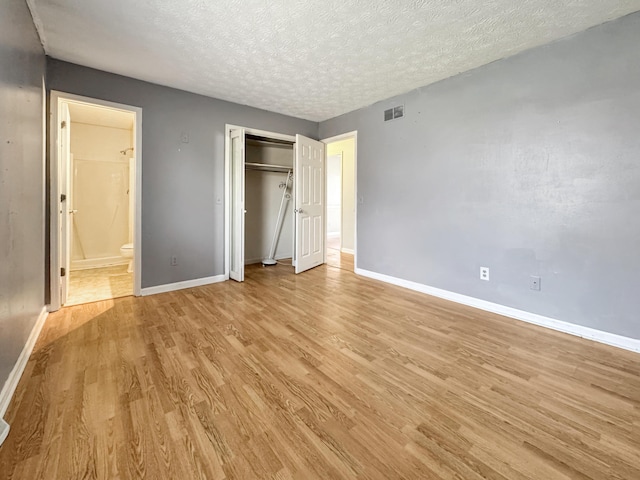 unfurnished bedroom with a textured ceiling, light wood-style flooring, visible vents, and baseboards