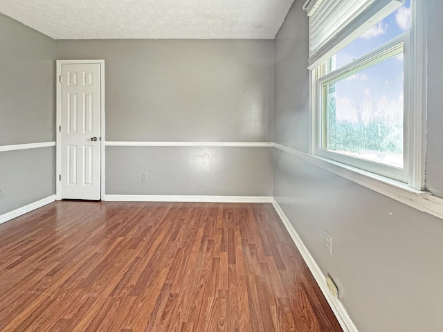 spare room featuring a textured ceiling, wood finished floors, and baseboards