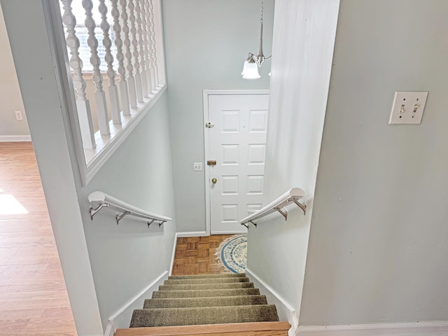 staircase with a notable chandelier and baseboards