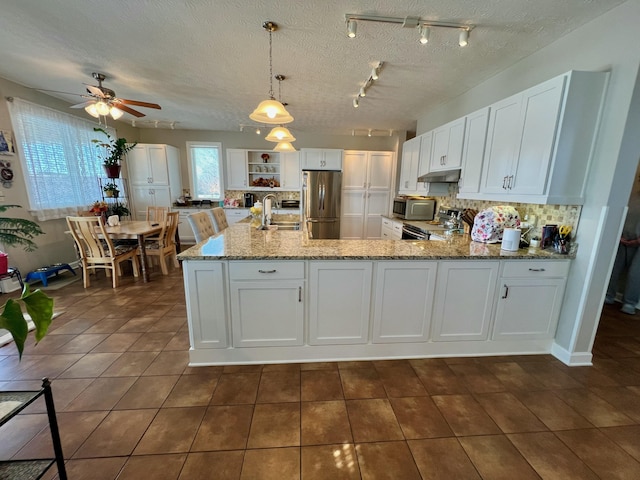 kitchen with hanging light fixtures, stainless steel appliances, white cabinets, and a sink