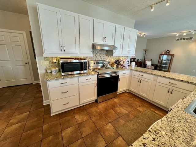 kitchen featuring appliances with stainless steel finishes, white cabinetry, under cabinet range hood, and a peninsula