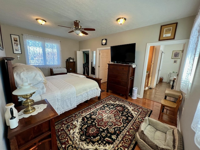 bedroom with baseboards, a textured ceiling, a ceiling fan, and wood finished floors