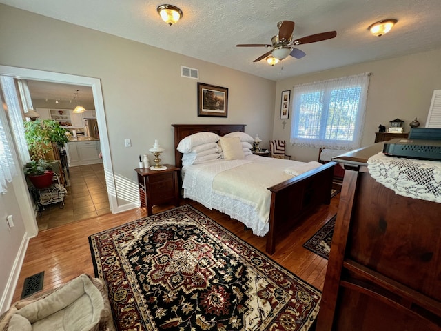 bedroom featuring a textured ceiling, visible vents, wood finished floors, and ensuite bathroom