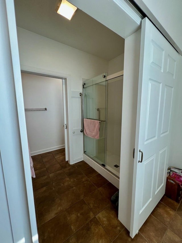 full bath featuring a shower stall and baseboards