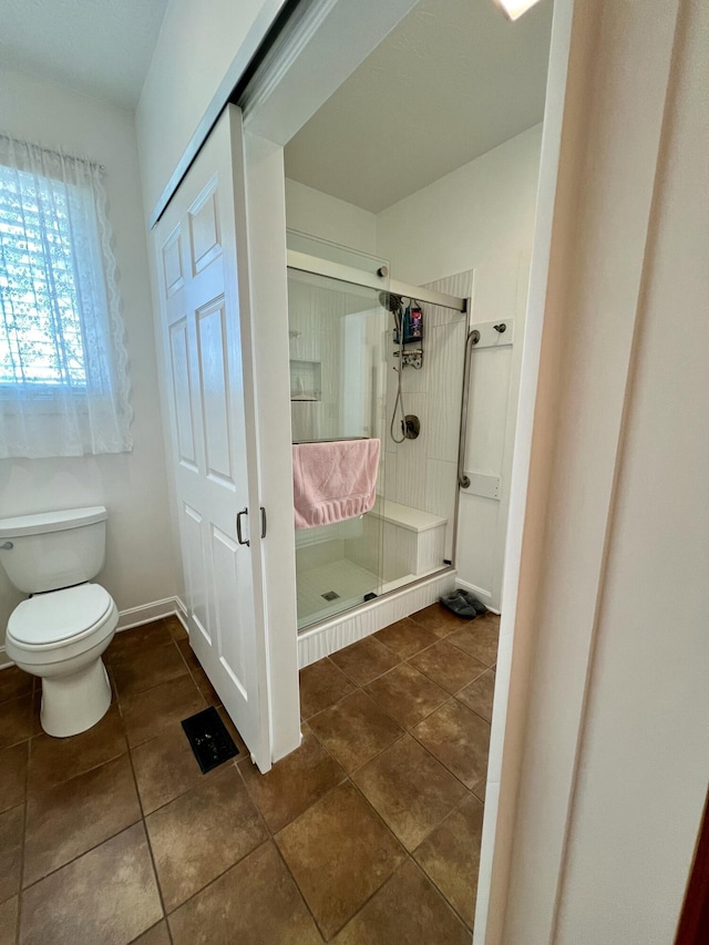 full bathroom featuring tile patterned flooring, a shower stall, toilet, and baseboards