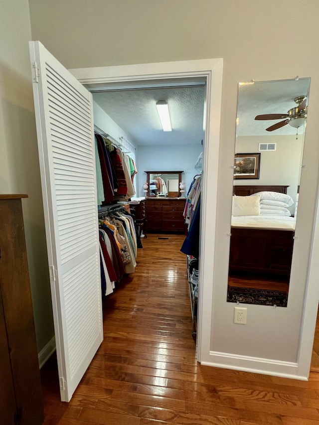 walk in closet featuring dark wood-style floors, ceiling fan, and visible vents