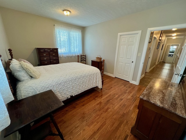 bedroom with a textured ceiling, baseboards, and wood finished floors