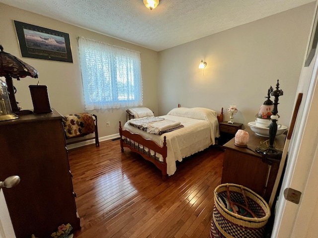 bedroom featuring baseboards, dark wood finished floors, and a textured ceiling