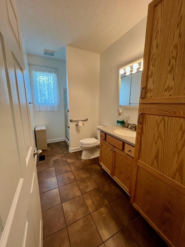 full bath featuring toilet, a textured ceiling, vanity, tile patterned flooring, and baseboards