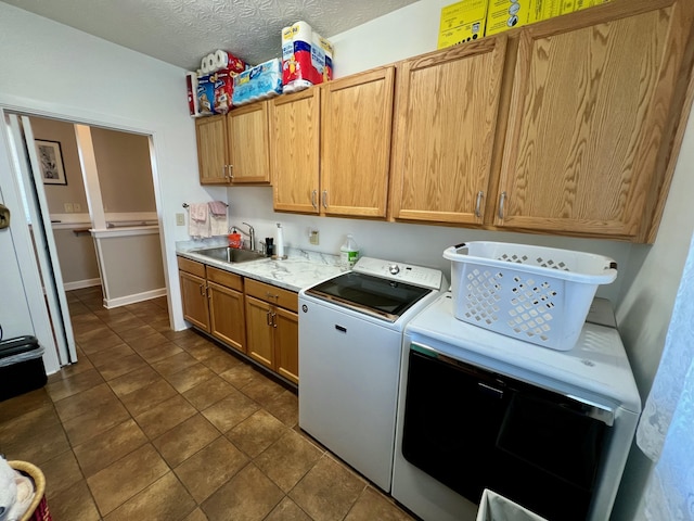 kitchen featuring a textured ceiling, light countertops, washing machine and clothes dryer, and a sink