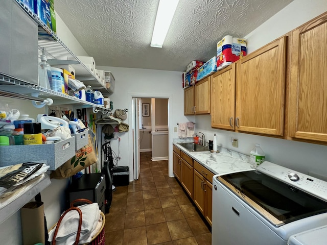 kitchen with independent washer and dryer, light countertops, a textured ceiling, dark tile patterned floors, and a sink