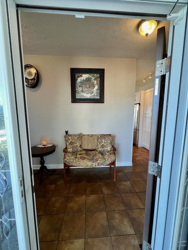 living area with a textured ceiling, dark tile patterned floors, and baseboards