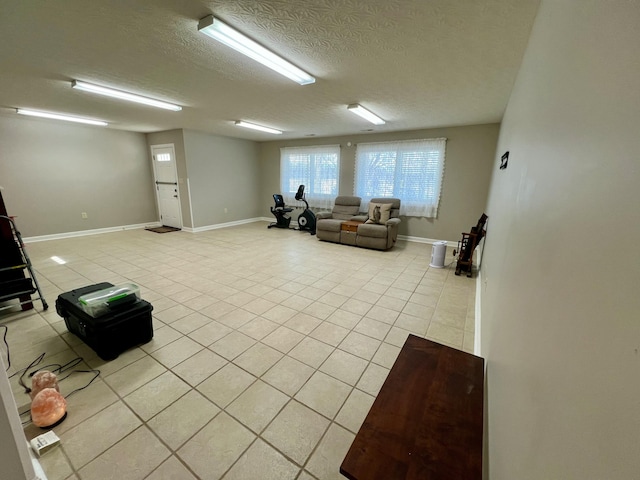 living room with light tile patterned floors, baseboards, and a textured ceiling