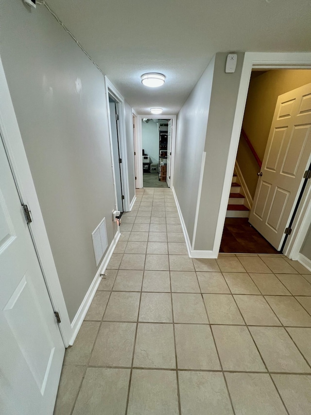 hall featuring light tile patterned floors, baseboards, stairway, and visible vents